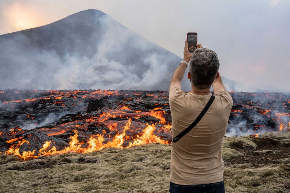FOTO: Un hombre toma fotografías mientras la lava emerge de una fisura del volcán Fagradalsfjall cerca de la montaña Litli-Hrutur, al suroeste de Reykjavik, Islandia, el 10 de julio de 2023.