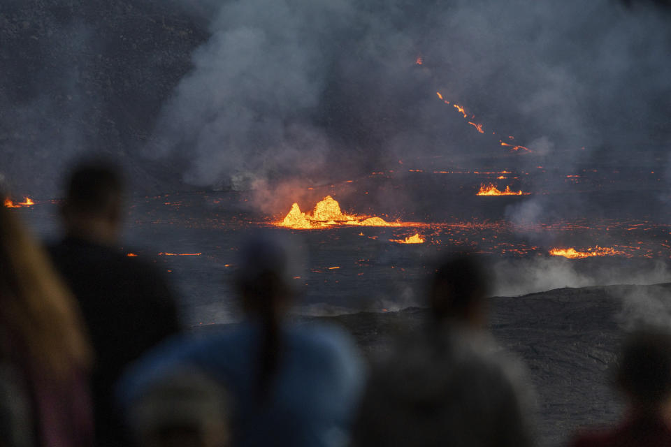 Los espectadores observan cómo fluye la lava desde la erupción.