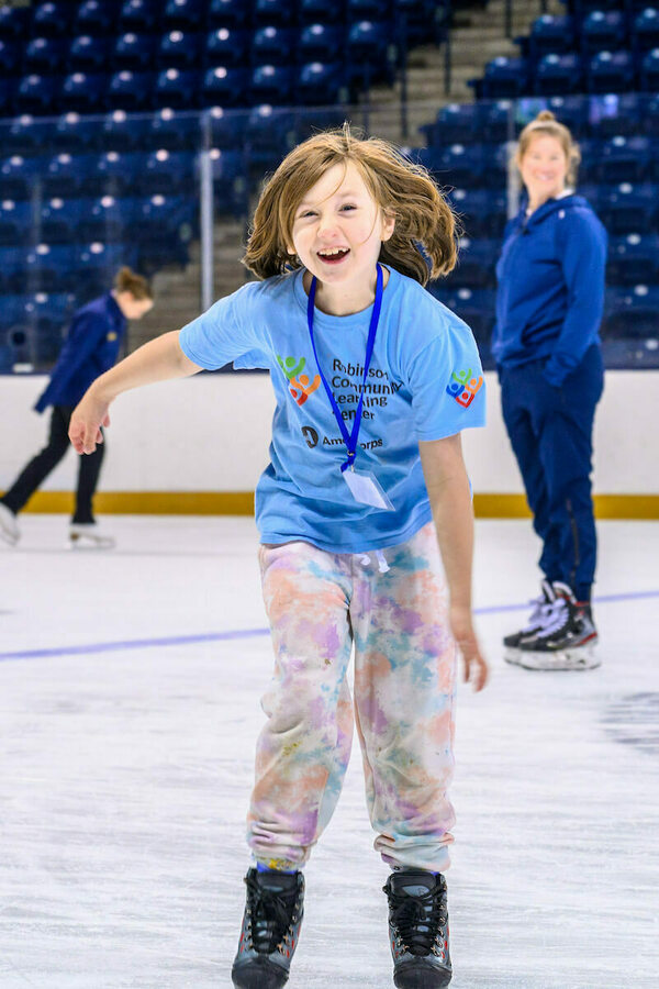 Se ríe a un niño con una camiseta azul T para el Robinson Community Learning Center y una corbata pintando dulces en la plaza de hielo.