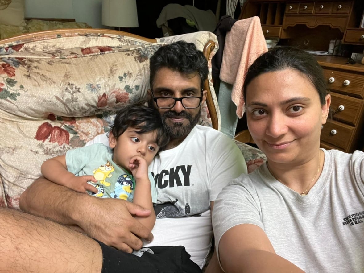 Una mujer, un hombre y un bebé son visibles para la selfie mientras está sentado en el sofá.