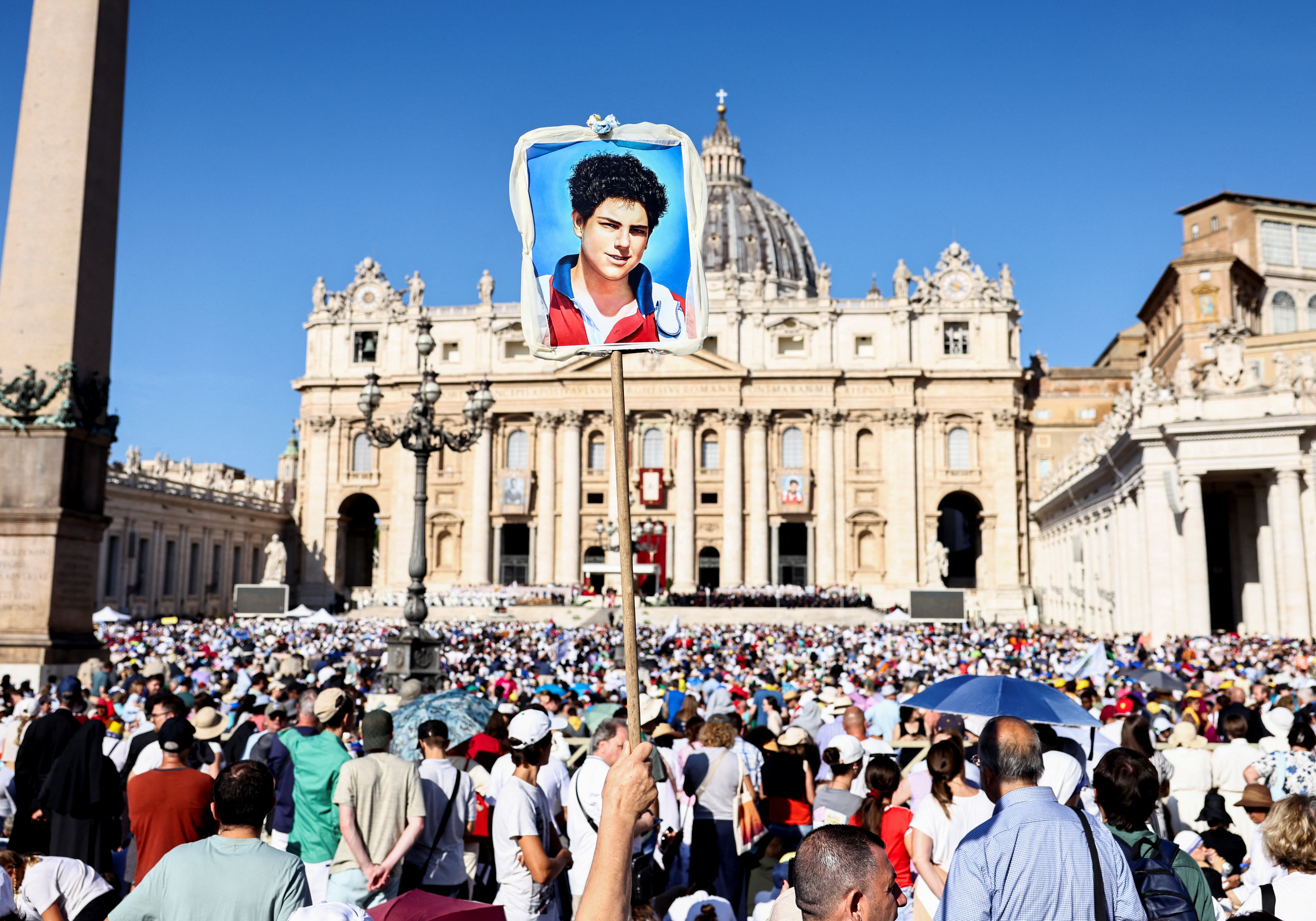 En el Vaticano, durante la misa de canonización, un hombre sostiene una obra de arte de Carlo Acuzzi.