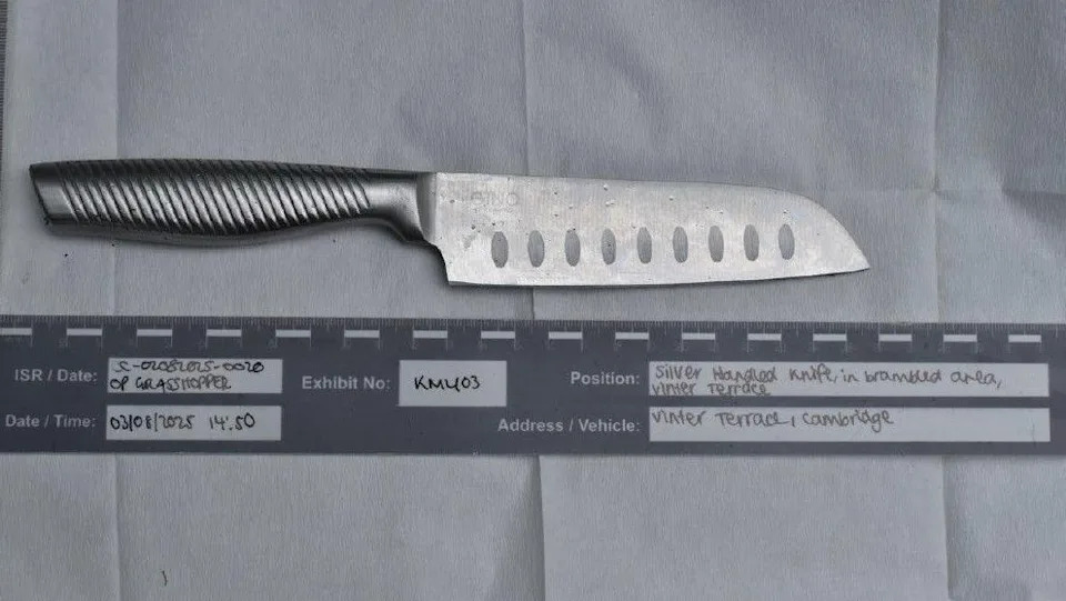 Imagen de la policía con un cuchillo de pelar de hoja grande colocado encima de una hoja de papel con etiquetas debajo que muestran la fecha y hora del descubrimiento, el número de prueba y el lugar donde se encontró.