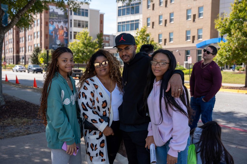 Una familia de cuatro personas posa para una fotografía frente a las residencias universitarias de la Universidad de Augusta.
